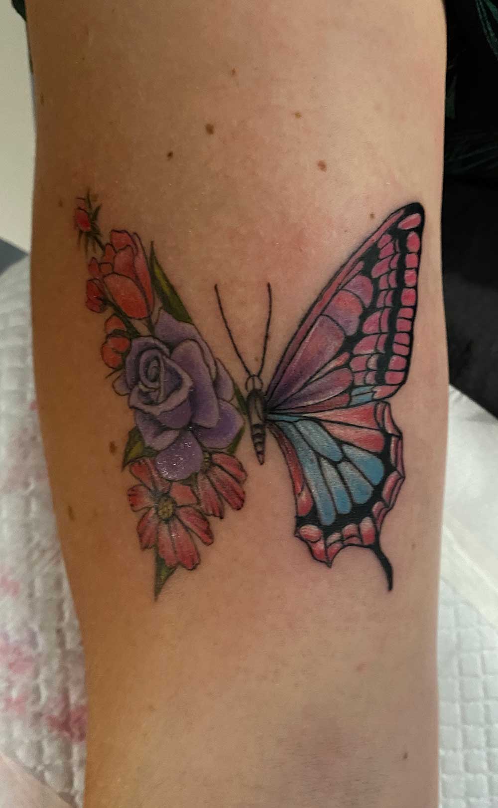 Schmetterling und Blumen Tattoo in Pastellfarben