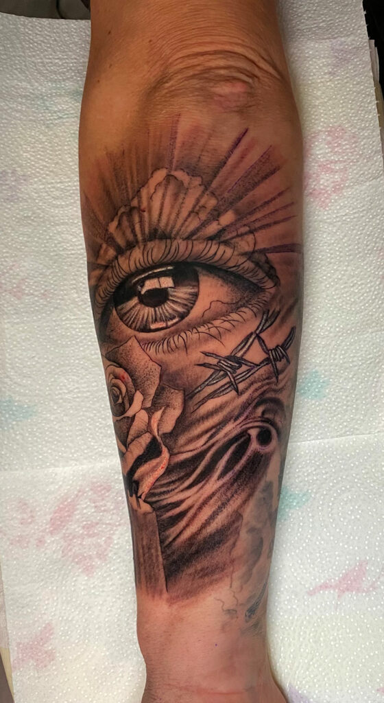 Eye, rose and candle tattoo on the arm
